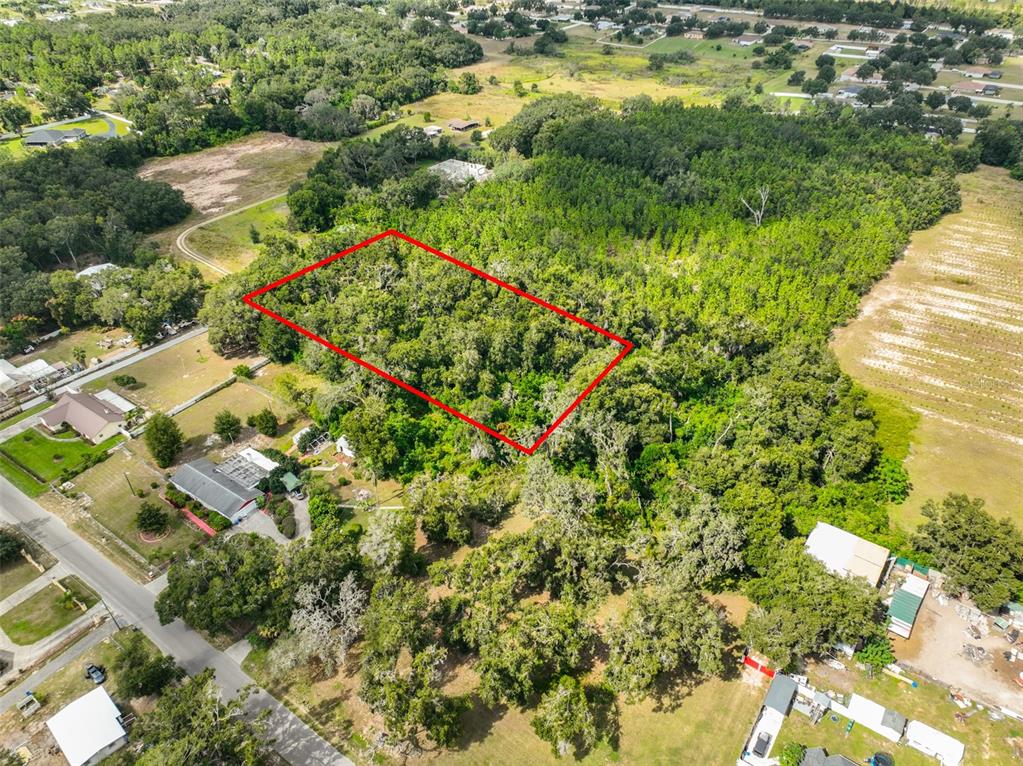 An aerial view shows a rectangular plot of land outlined in red amidst wooded terrain — STARK ROAD, SEFFNER, FL