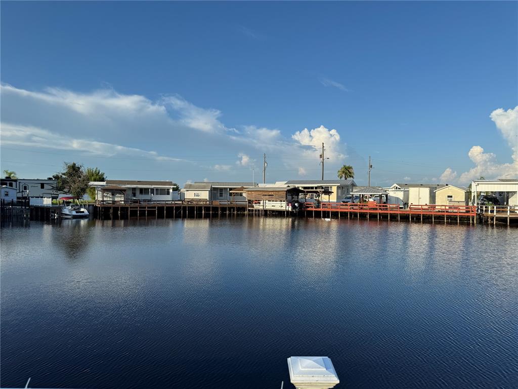 A row of mobile homes sits along a wooden dock overlooking a calm body of water — 1405 STARBOARD DRIVE, ST CLOUD, FL