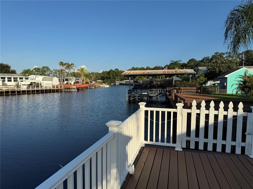A wooden deck with a white railing overlooks a canal with boat docks and houses — 1405 STARBOARD DRIVE, ST CLOUD, FL