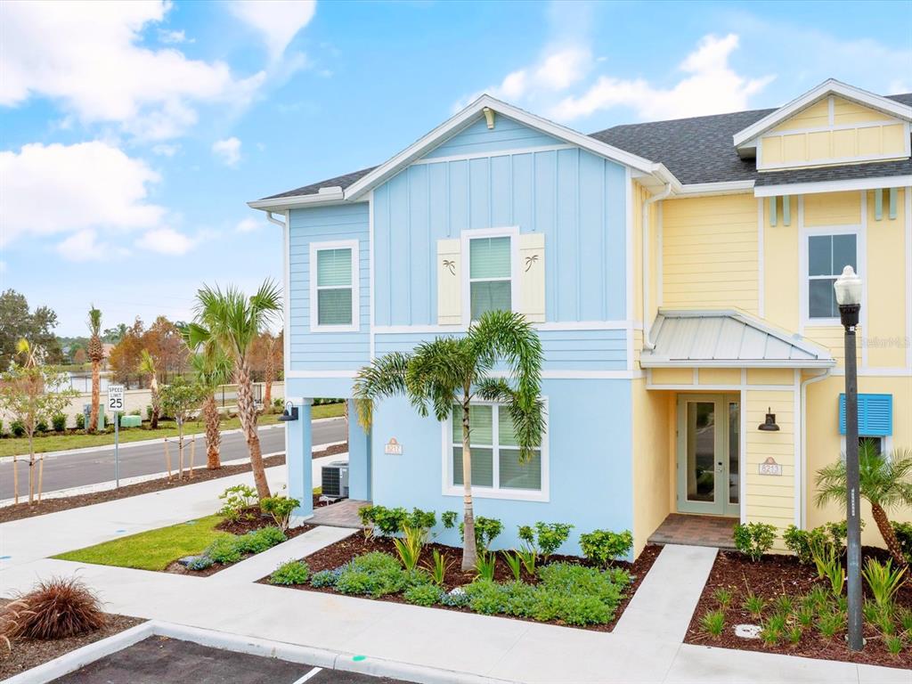 A two-story blue and yellow townhouse features a palm tree in the front yard — 8217 SURF STREET, KISSIMMEE, FL