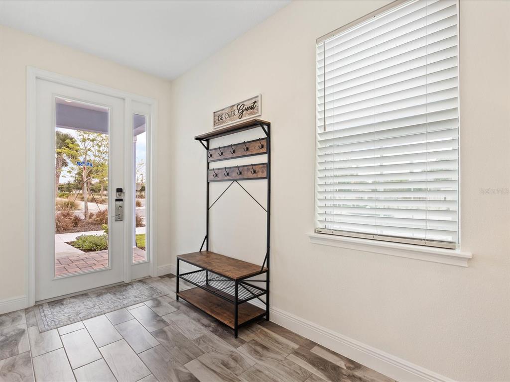 An entryway features a metal and wood coat rack, tile flooring, and a glass-paneled front door — 8217 SURF STREET, KISSIMMEE, FL