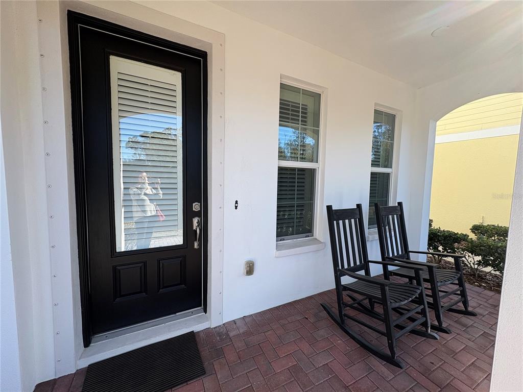 A front porch features a black door, two black rocking chairs, and brick pavers — 103 CUTLASS WAY, OLDSMAR, FL