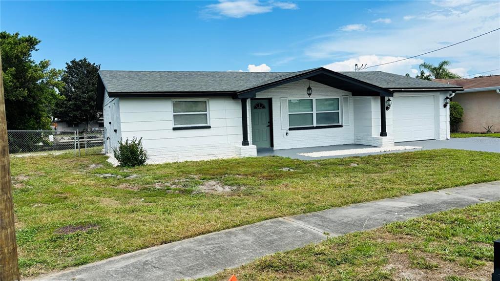 A white brick house features a black-trimmed entryway, a garage, and a concrete driveway — 1346 CHANCELLOR DRIVE, HOLIDAY, FL
