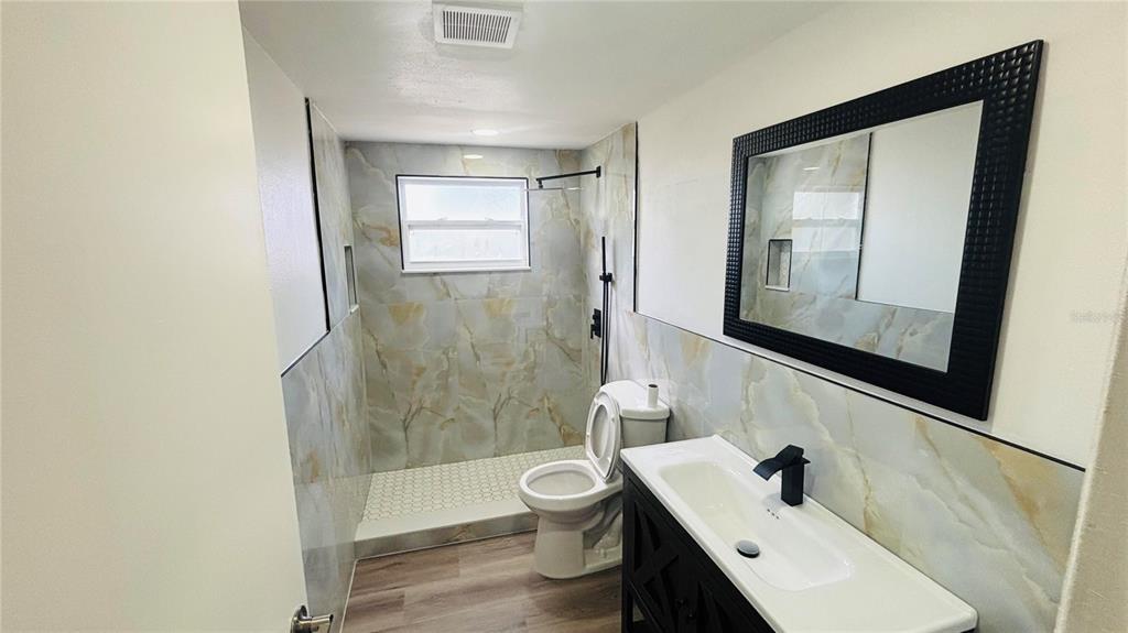 A kitchen features white cabinets, gold hardware, stainless steel appliances, and light-colored countertops — 1346 CHANCELLOR DRIVE, HOLIDAY, FL