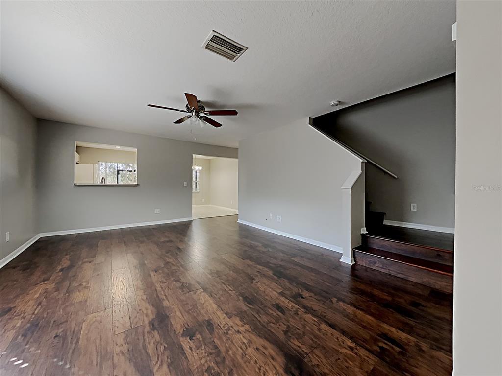An open living area features dark wood-look flooring, a ceiling fan, and a staircase — 404 SUMMER SAILS DRIVE, VALRICO, FL