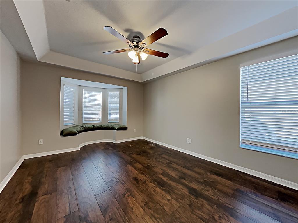 An empty room with dark wood flooring, a ceiling fan, and a built-in window seat — 404 SUMMER SAILS DRIVE, VALRICO, FL