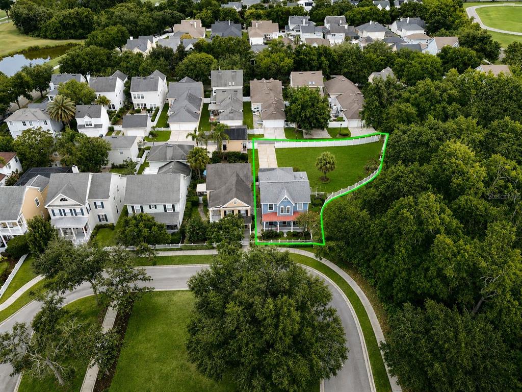 An aerial view shows a residential house with a fenced backyard bordering a wooded area — 600 CANNE PLACE, CELEBRATION, FL