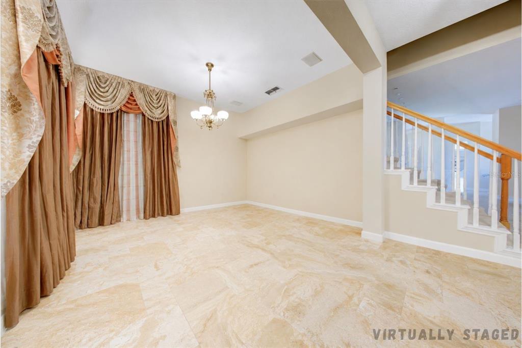 An empty dining room features tile flooring, a chandelier, and heavy curtains over a window — 600 CANNE PLACE, CELEBRATION, FL