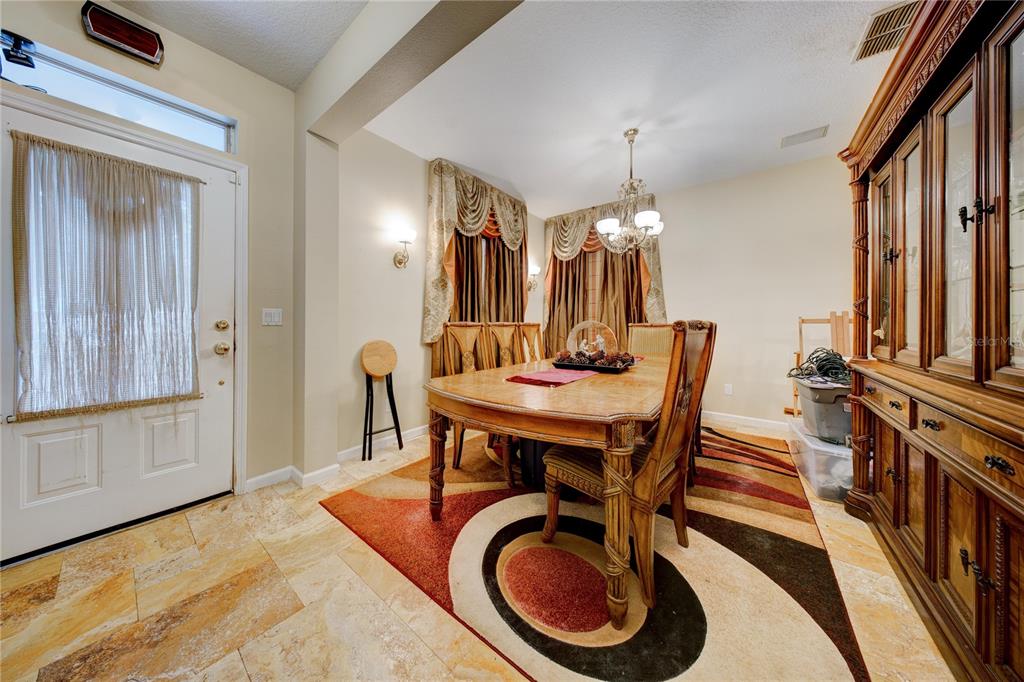 A dining room features a wooden table, patterned rug, tile flooring, and a large hutch — 600 CANNE PLACE, CELEBRATION, FL