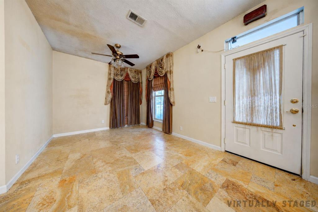 An empty room with tan tile flooring, a ceiling fan, and a white front door — 600 CANNE PLACE, CELEBRATION, FL