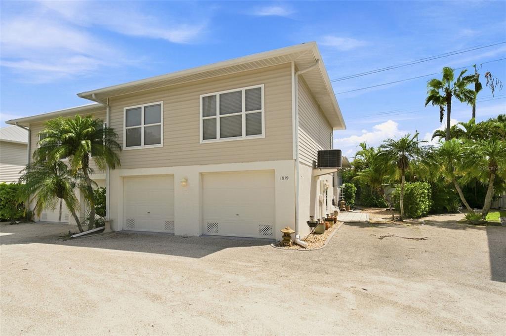 A tan house exterior features a white front door, stairs, and a gravel yard area — 1819 HIGHLAND ROAD, OSPREY, FL