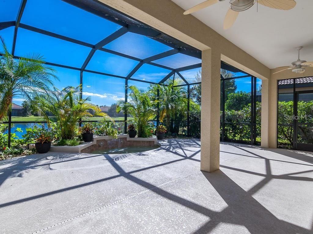 A covered patio with a screened enclosure, a small water feature, and a view of water — 1884 BATELLO DRIVE, VENICE, FL