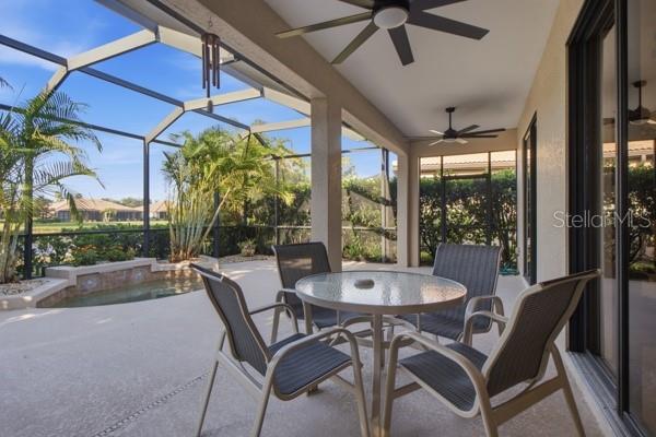 A covered patio features a round glass table, four chairs, ceiling fans, and a screened enclosure — 1884 BATELLO DRIVE, VENICE, FL