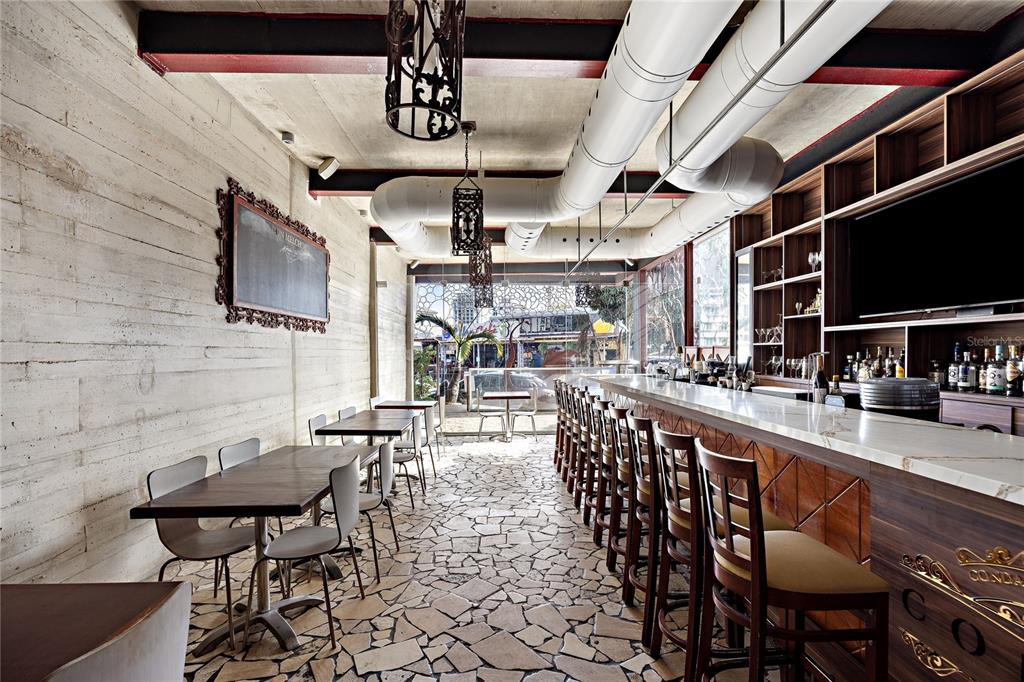 A bar area features a stone floor, wooden tables, a long marble counter, and exposed ductwork — 1105 MAGDALENA AVENUE UNIT Condal, SAN JUAN, PR