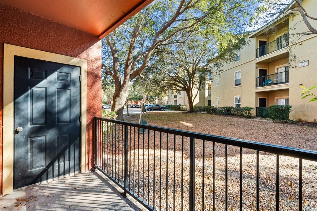 A view from a covered balcony overlooking a grassy courtyard and a multi-story apartment building — 132 VISTA VERDI CIRCLE UNIT 136, LAKE MARY, FL