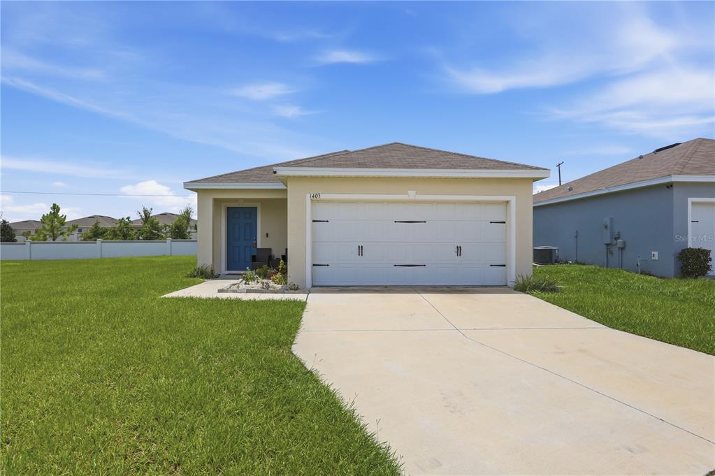 A blue front door is set into the recessed entryway of a beige stucco house — 1403 MADISON CIRCLE, HAINES CITY, FL