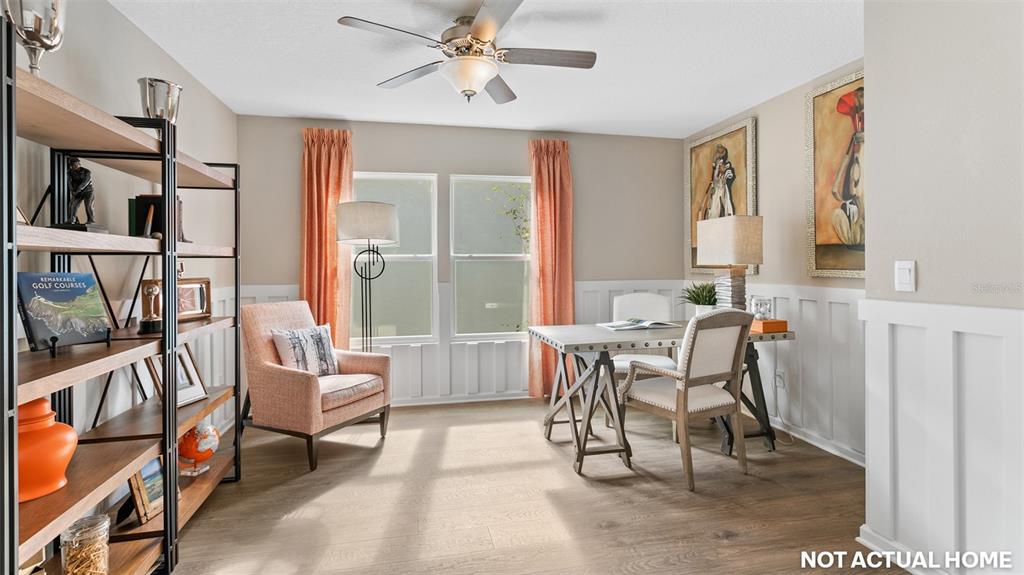 This home office features a desk, an armchair, wood-look flooring, and white wainscoting — 36 HARDWOOD TRAIL, PALM COAST, FL