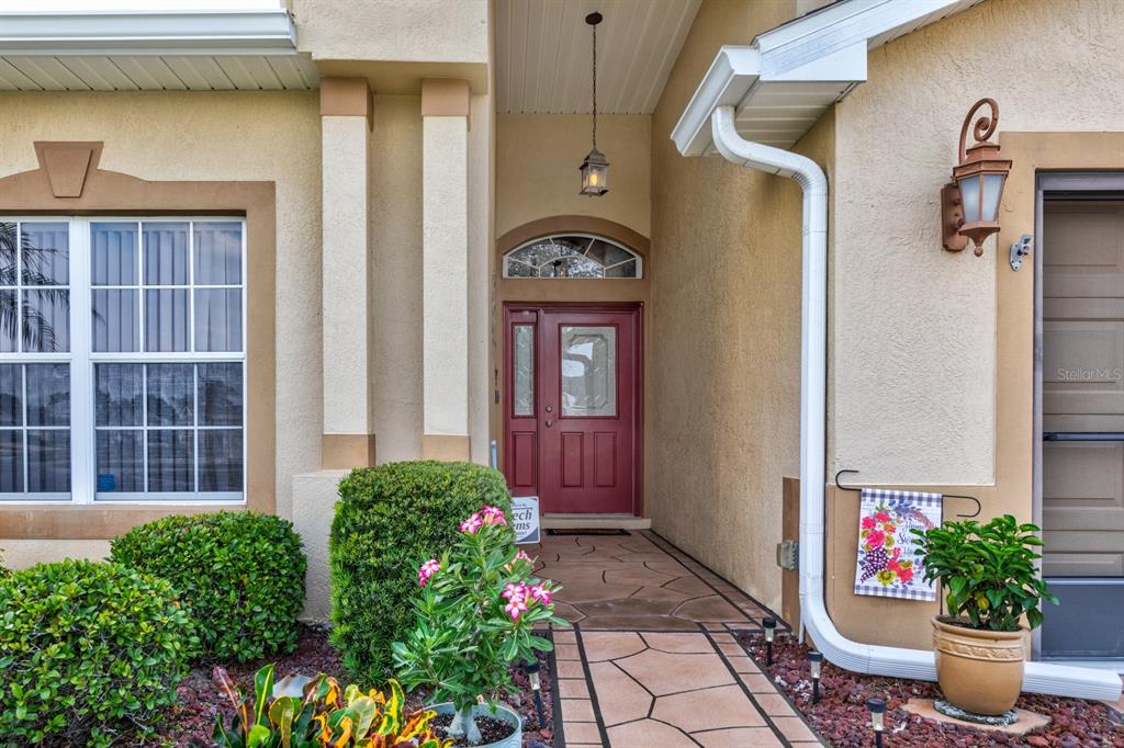 The exterior view shows a red front door, a stone walkway, and landscaping — 5615 CELEBRATION WAY, LEESBURG, FL