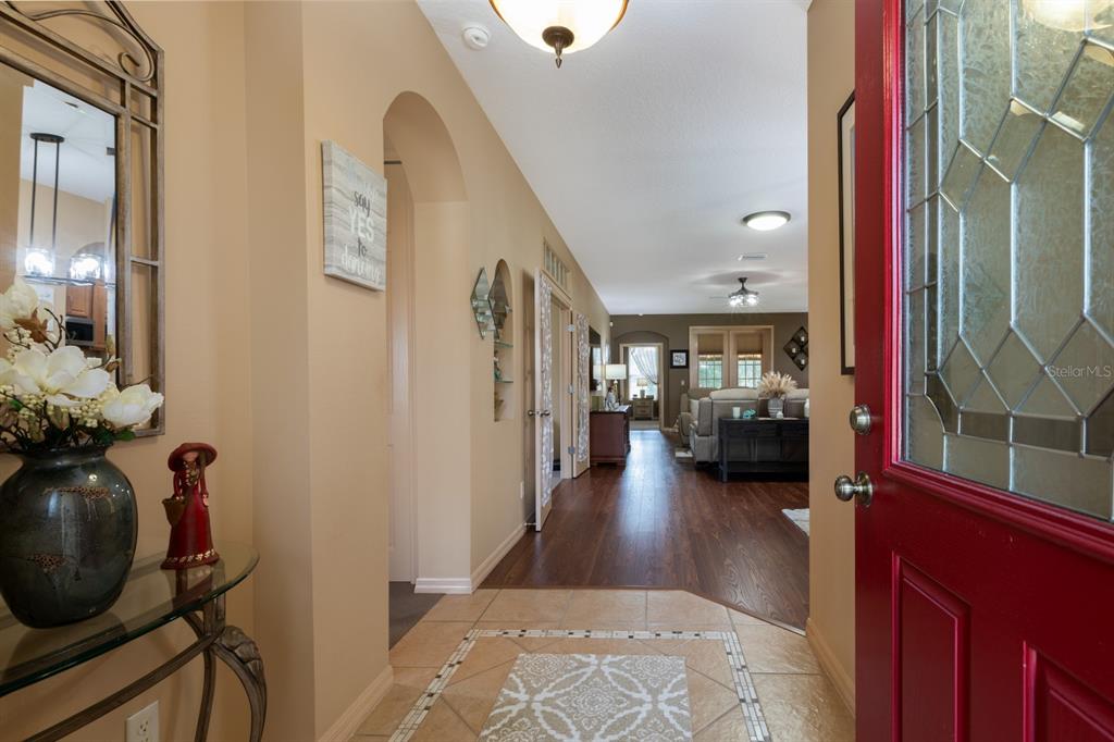 A bright entryway with tile flooring leads into a living area with dark wood floors — 5615 CELEBRATION WAY, LEESBURG, FL