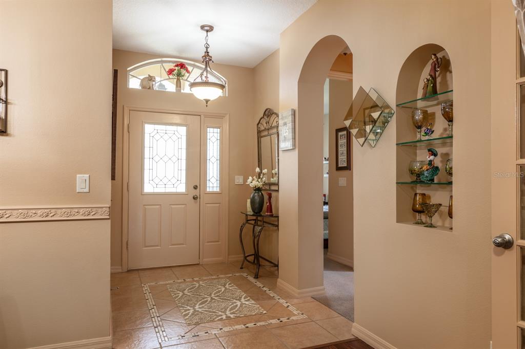 An entryway features a tiled floor, a front door with sidelights, and an arched wall niche — 5615 CELEBRATION WAY, LEESBURG, FL