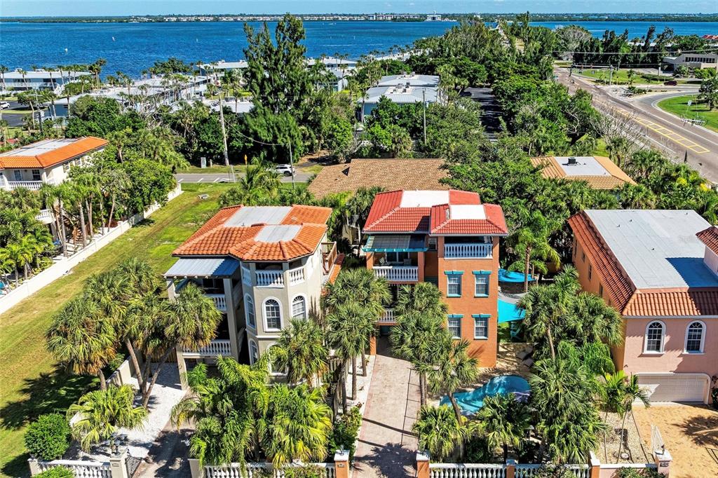 A paved driveway leads to a three-story orange house with balconies and a pool — 4003 5TH AVENUE, HOLMES BEACH, FL