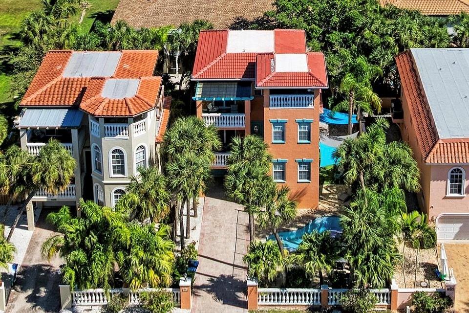 An orange three-story house features a swimming pool, patio, and balconies in the backyard — 4003 5TH AVENUE, HOLMES BEACH, FL