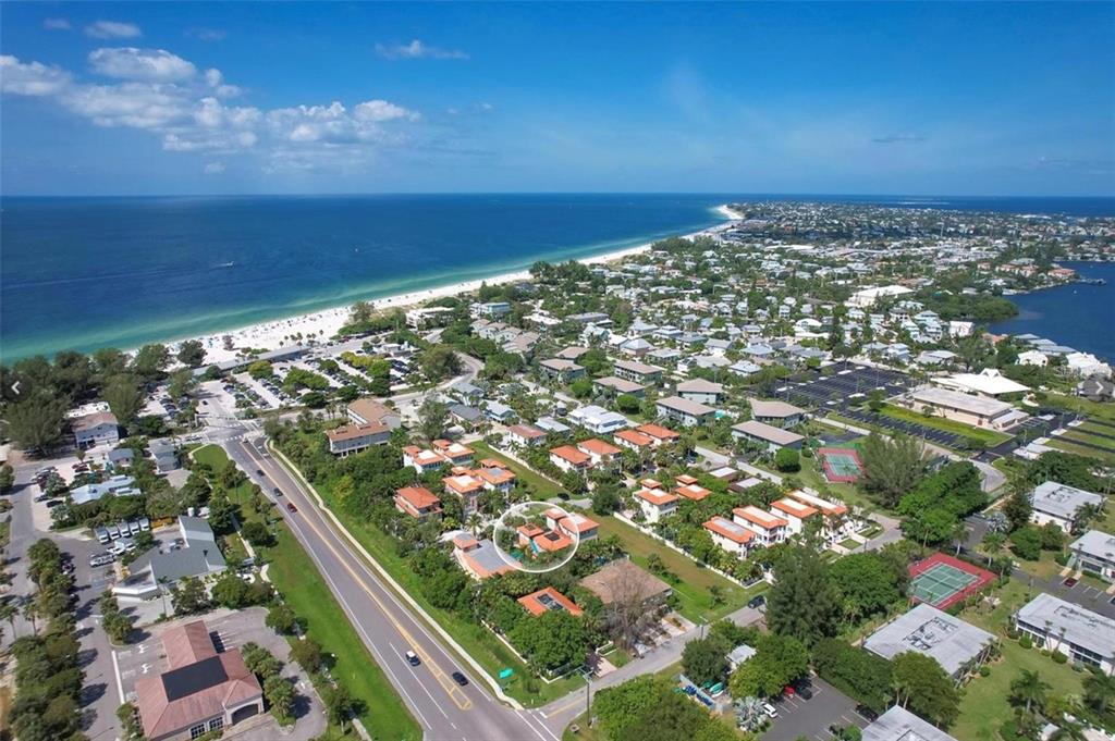 A covered balcony features wicker furniture with blue cushions, a glass-topped table, and orange walls — 4003 5TH AVENUE, HOLMES BEACH, FL
