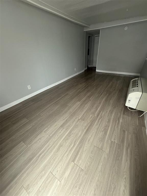 An empty room with light gray walls, wood-look flooring, and a wall-mounted air conditioning unit — 515 BON AIR STREET UNIT 1A, LAKELAND, FL