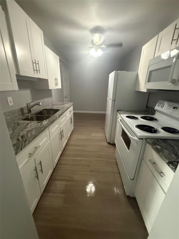 A galley kitchen features white cabinets, marble-patterned countertops, and stainless steel appliances — 515 BON AIR STREET UNIT 1A, LAKELAND, FL