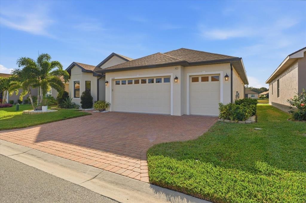 A single-story house with a beige stucco exterior, a brick paver driveway, and a three-car garage — 6308 PINEHURST LOOP, WINTER HAVEN, FL