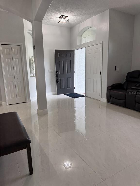 A living room features a beige sofa, a patterned armchair, and a brown ottoman on tile — 14 WAYLAND PLACE, PALM COAST, FL