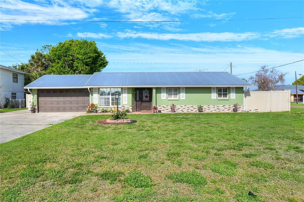 A single-story house with a green exterior, metal roof, and attached garage — 6108 FAIRWAY BOULEVARD, APOLLO BEACH, FL
