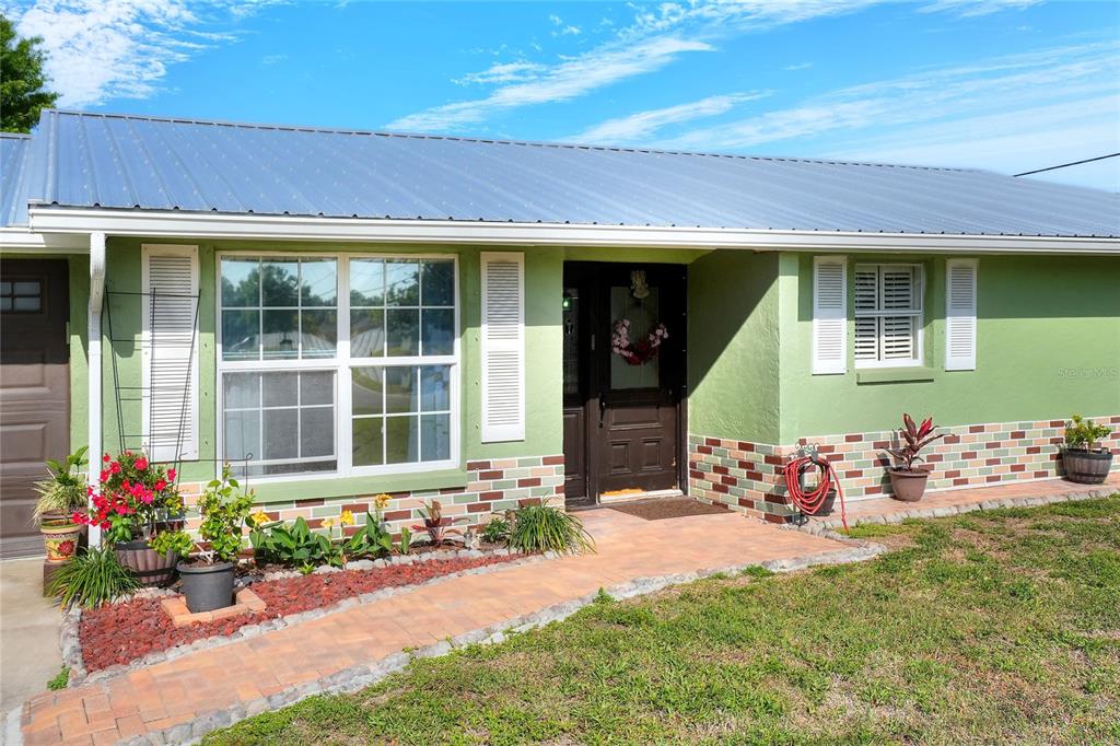 A single-story house with green siding, a metal roof, and a brick-patterned lower exterior — 6108 FAIRWAY BOULEVARD, APOLLO BEACH, FL