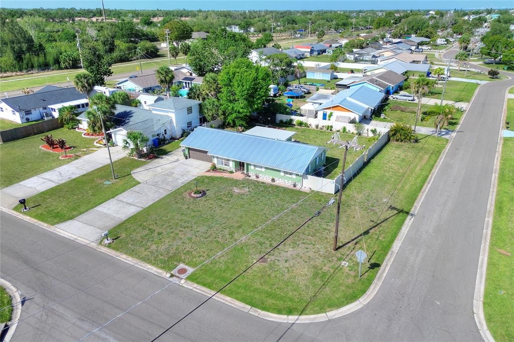 An aerial view shows a single-story house with a blue metal roof on a corner lot — 6108 FAIRWAY BOULEVARD, APOLLO BEACH, FL
