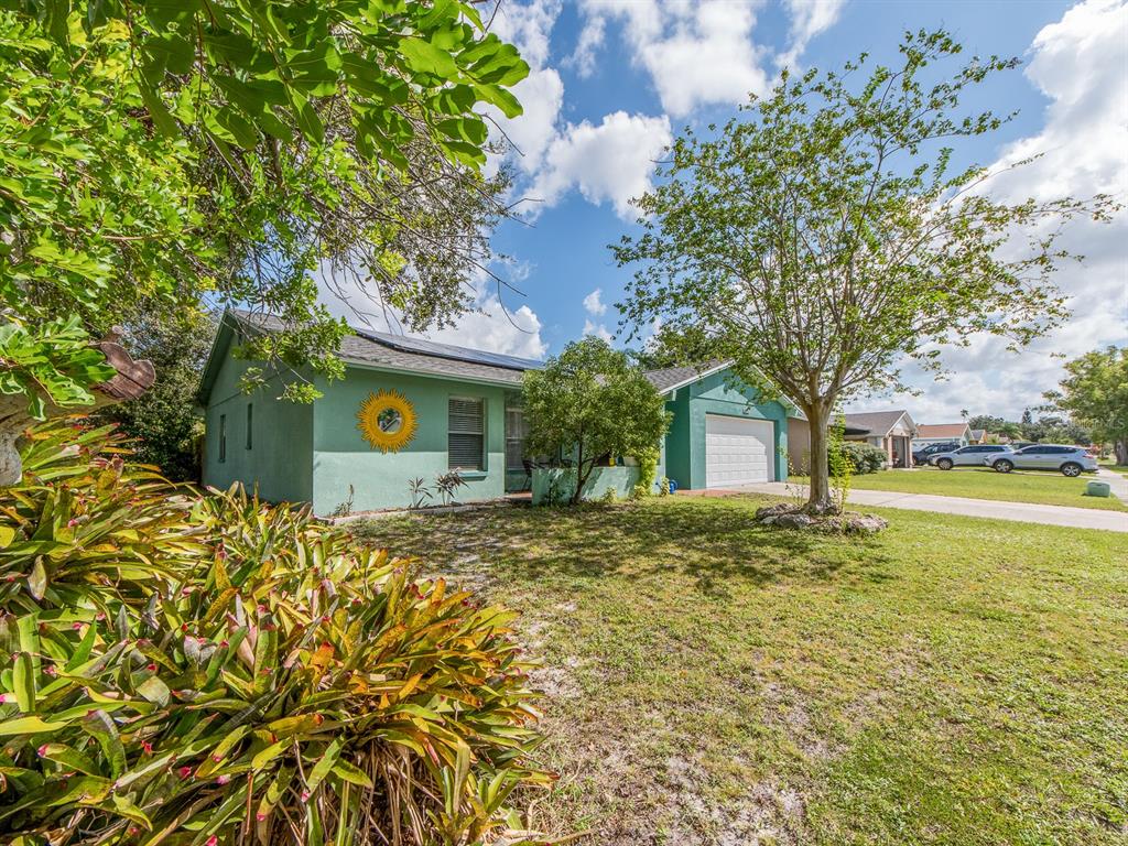 A light green single-story house with a garage, solar panels, and a front yard — 1832 SETON DRIVE, CLEARWATER, FL