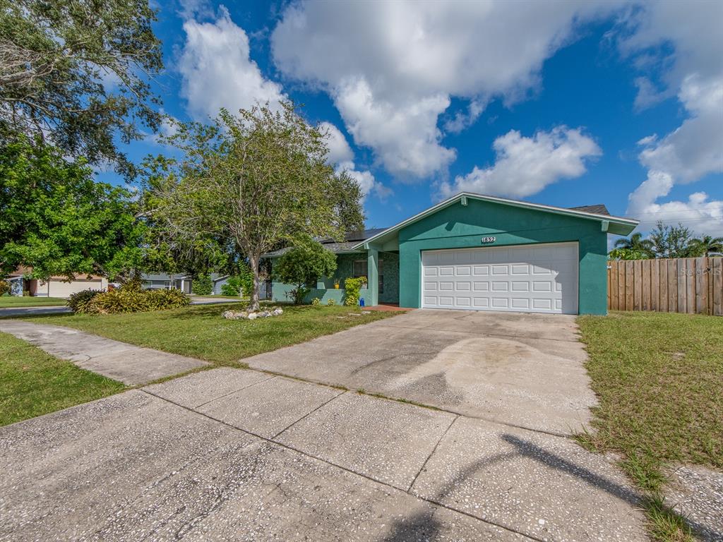 A teal single-story house with a white garage door and a concrete driveway — 1832 SETON DRIVE, CLEARWATER, FL