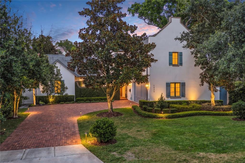 A two-story white stucco house with blue shutters and a brick driveway at dusk — 1597 OAKHURST AVENUE, WINTER PARK, FL