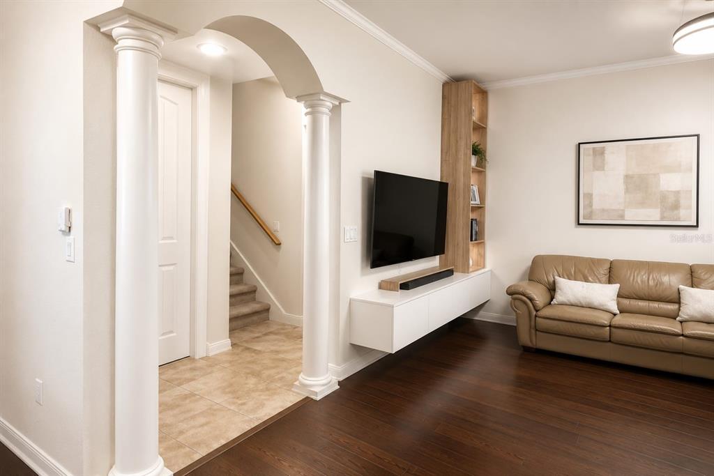 A living room features a wall-mounted television, floating console, shelving, and an arched entryway — 7060 VENTNOR DRIVE, WINDERMERE, FL