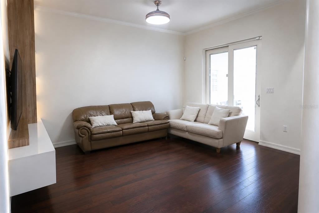A living room features dark wood floors, a brown leather sofa, and a cream sofa — 7060 VENTNOR DRIVE, WINDERMERE, FL