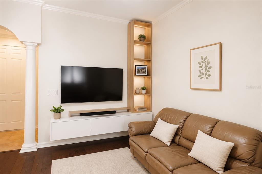 A living room features a wall-mounted television, floating white cabinet, and a tall wooden shelf — 7060 VENTNOR DRIVE, WINDERMERE, FL