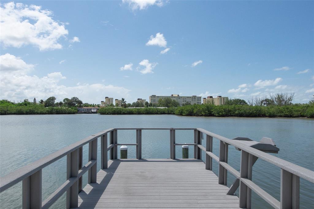 A wooden dock extends over calm water toward a distant shoreline with buildings and trees — 382 BOCA CIEGA POINT BOULEVARD S, ST PETERSBURG, FL