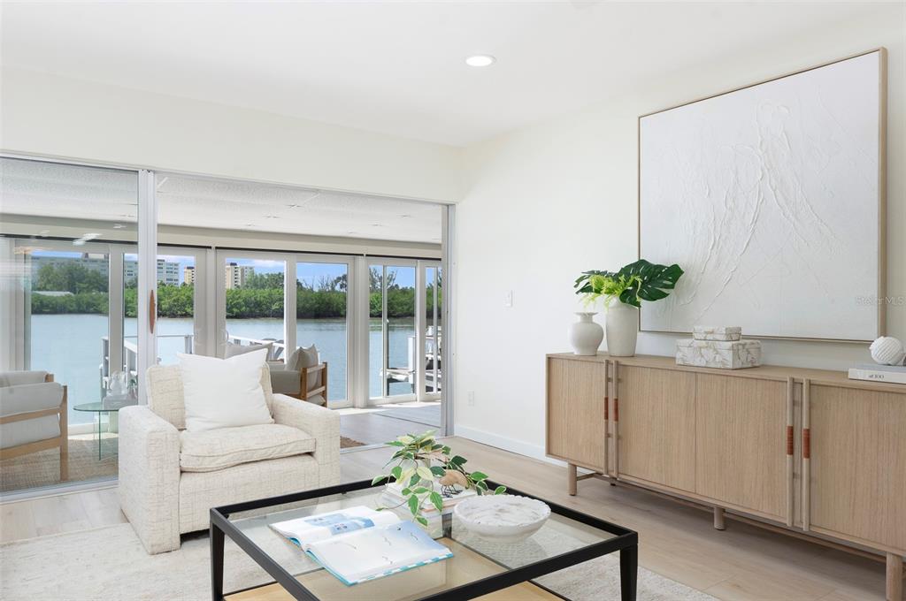 A bright living room features a glass coffee table, an armchair, and a wooden sideboard — 382 BOCA CIEGA POINT BOULEVARD S, ST PETERSBURG, FL