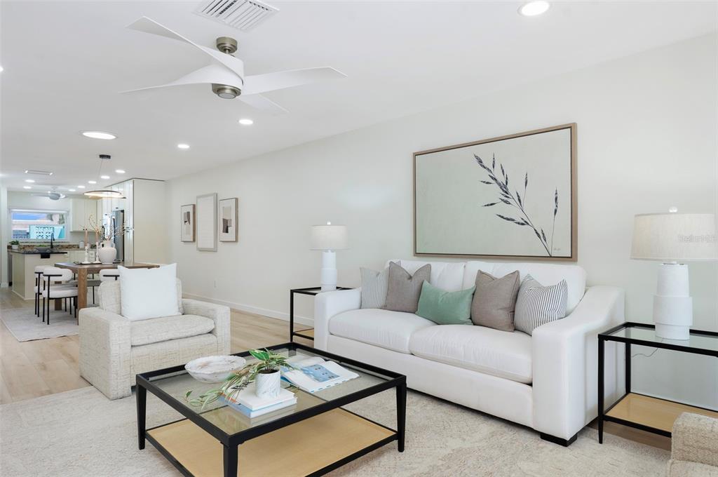 A bright living room features a white sofa, glass coffee table, and an open kitchen — 382 BOCA CIEGA POINT BOULEVARD S, ST PETERSBURG, FL