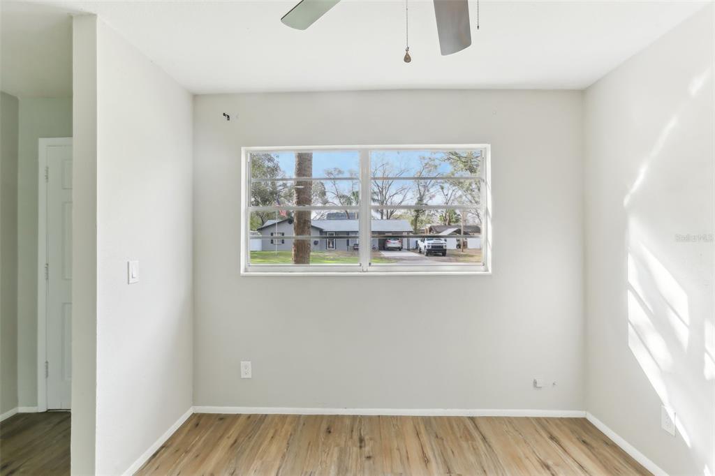 An empty room with light gray walls, wood-look flooring, and a large window — 7711 AMHERST STREET, TAMPA, FL