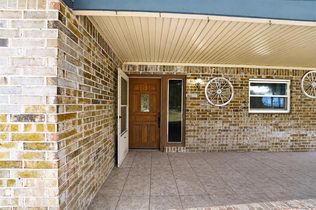 A brick-walled porch features a wooden front door, a side window, and decorative wagon wheels — 101 ALLEN DRIVE, PALATKA, FL