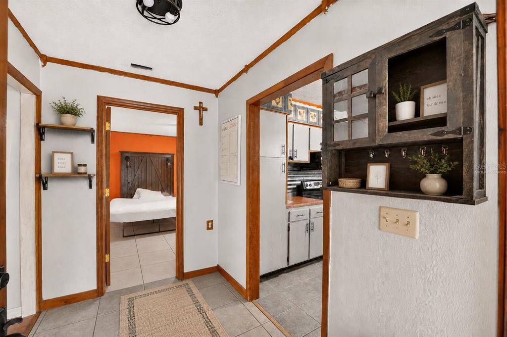 A hallway with tile floors leads to a bedroom and kitchen with wood trim accents — 101 ALLEN DRIVE, PALATKA, FL