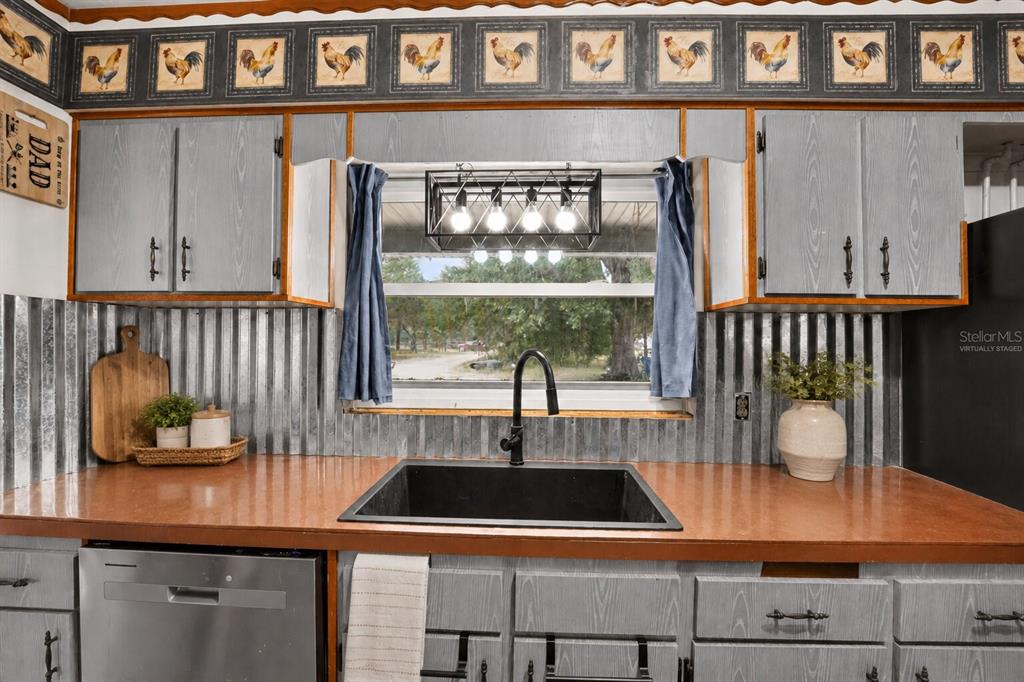 A kitchen features gray wood-grain cabinets, a corrugated metal backsplash, and a black farmhouse sink — 101 ALLEN DRIVE, PALATKA, FL