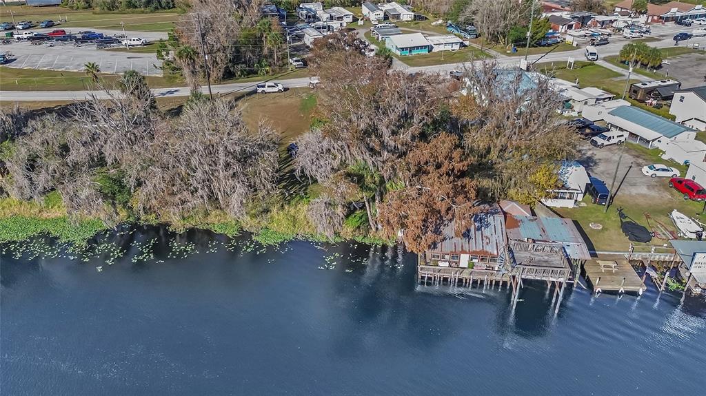 An aerial view shows a waterfront house with a wooden deck extending over the water — 55512 FRONT STREET, ASTOR, FL