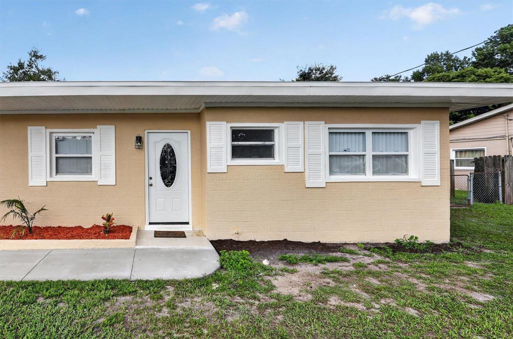 The exterior of a tan, single-story house features a white front door and windows with shutters — 208 PALMYRA DRIVE, ORLANDO, FL