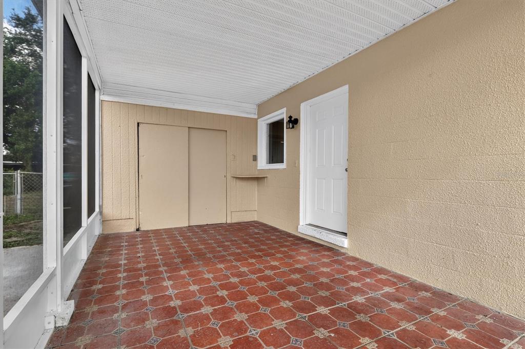A covered patio features red patterned tile flooring, a white door, and sliding storage closet doors — 208 PALMYRA DRIVE, ORLANDO, FL